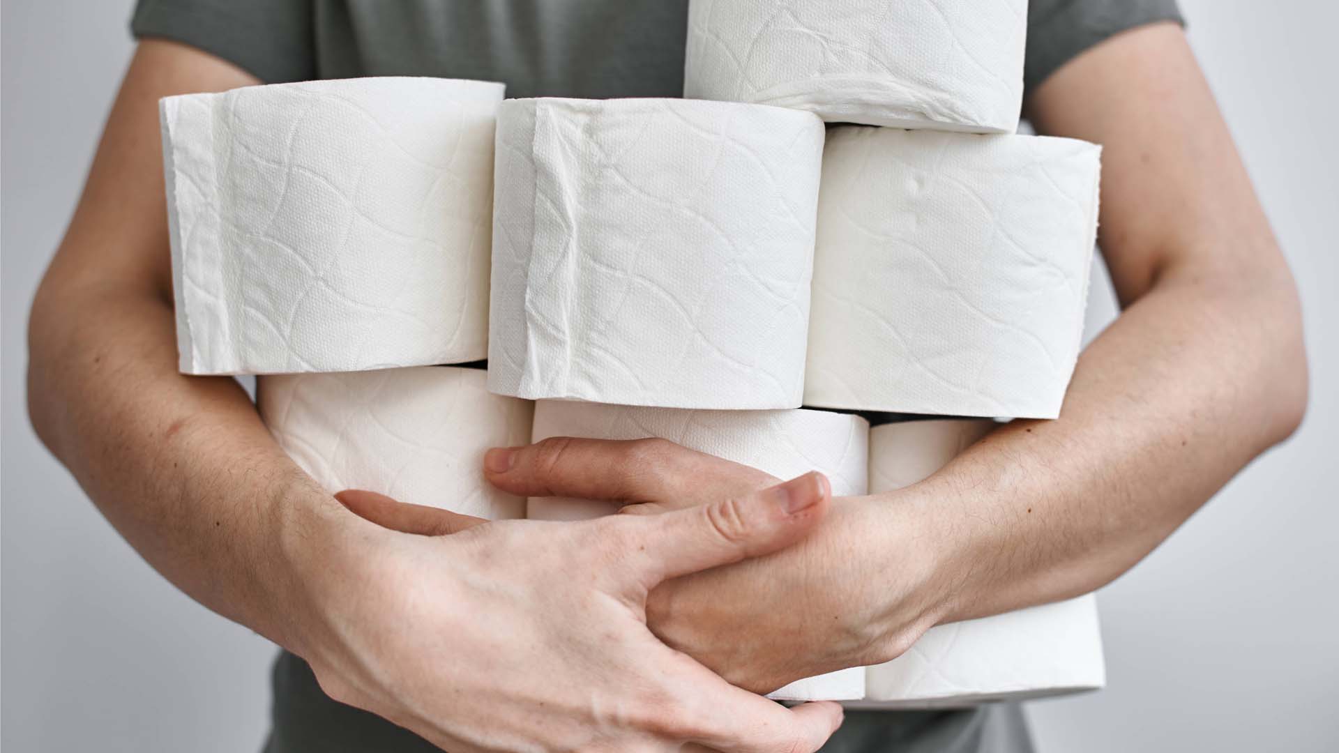 Close-up of a man holding several toilet rolls in his arms