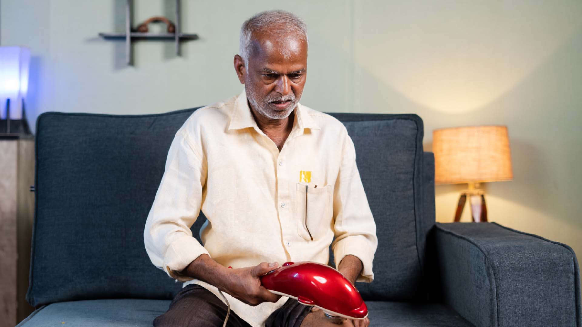 man sat on the sofa looking at his massage gun