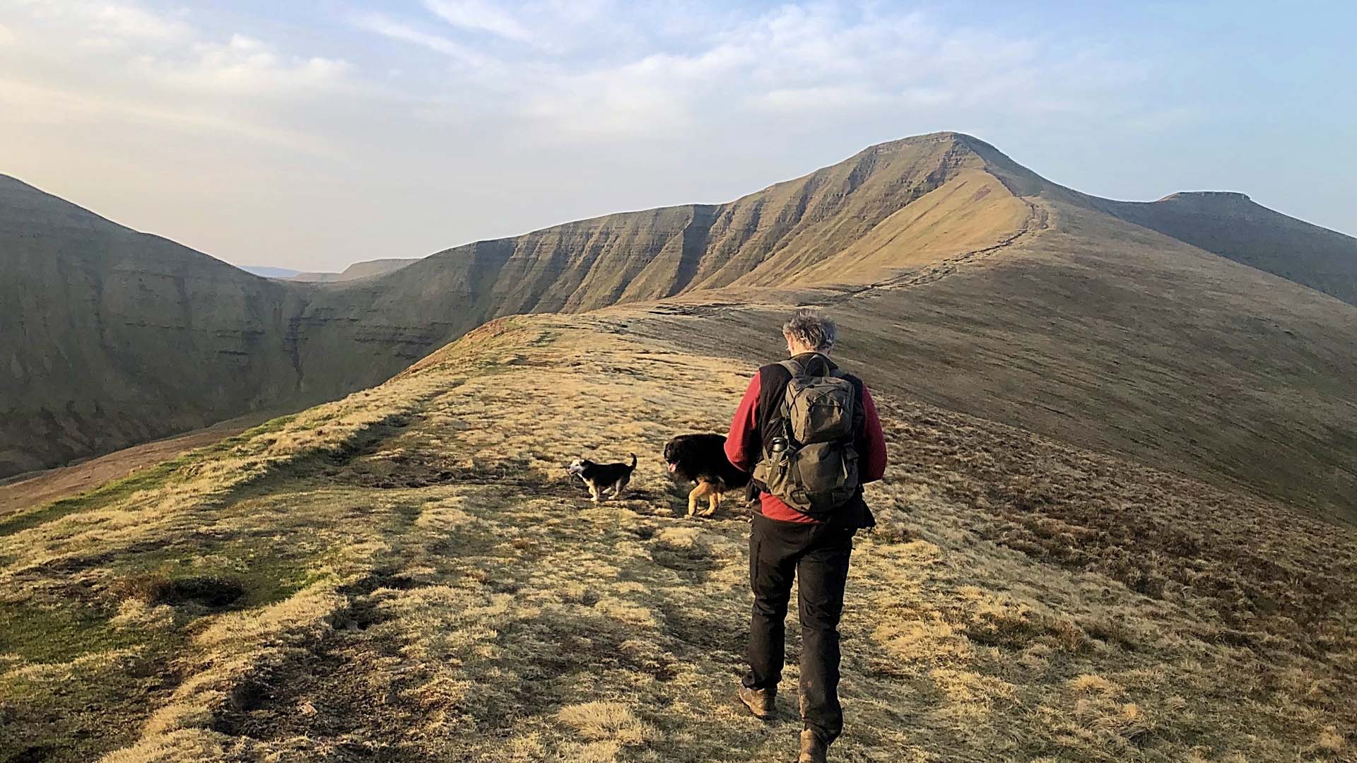A hiker walks off along the crest of a mountain