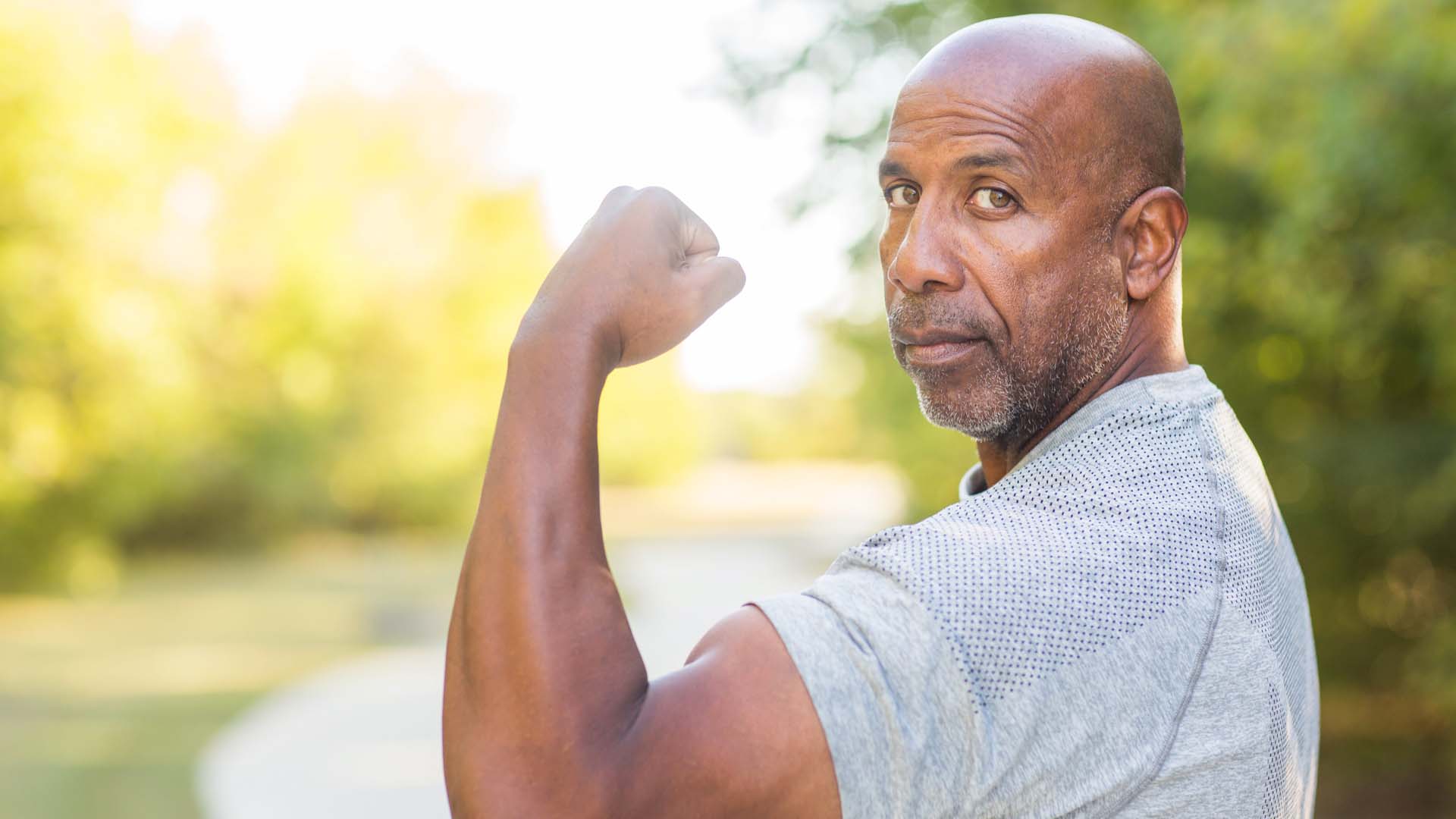 An older man with large biceps showing off his muscles
