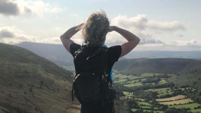 Saga's Phillipa Cherryson looks out onto rolling hills wearing a rucksack