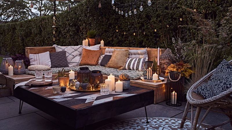 Garden bench covered with cushions and coffee tables laden with candles