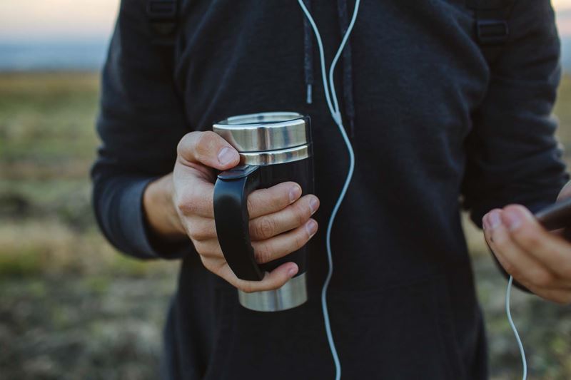 A person holding a thermos cup