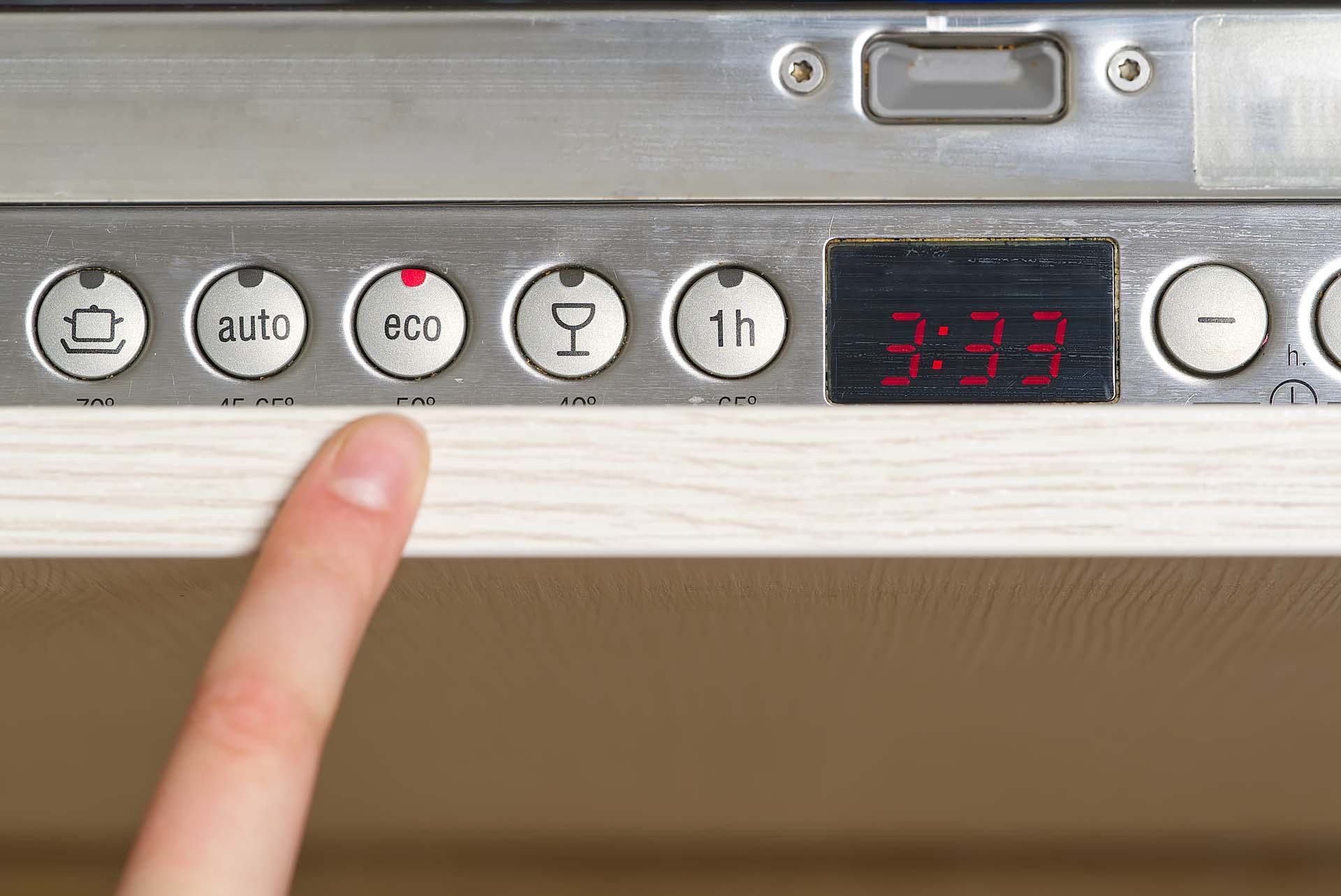 A finger pointing to the buttons on a dishwasher