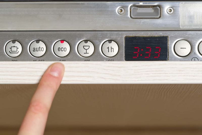 A finger pointing to the buttons on a dishwasher