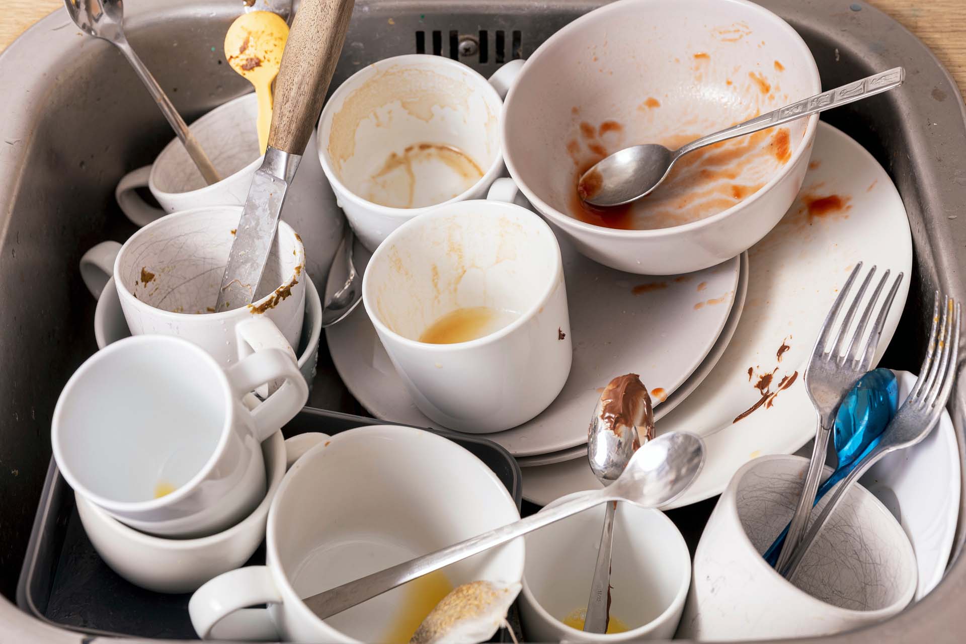 Dirty cups and dishes in washing up bowl