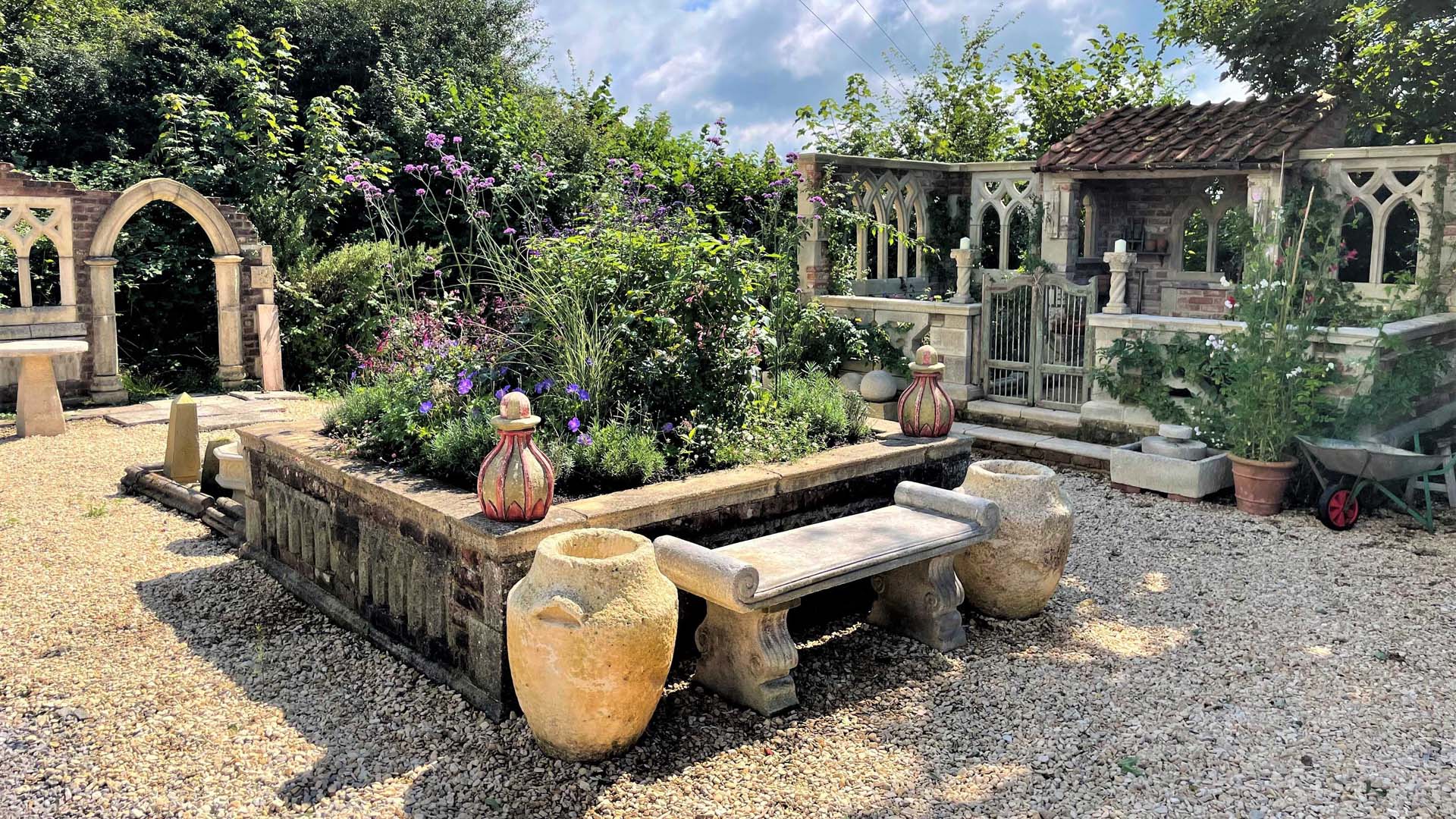 a walled garden with a variety of stone architectural features and planters