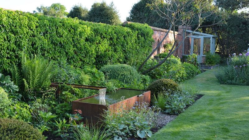 A walled garden with deep planting border and water feature