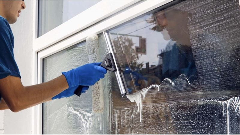 A close up of a person wearing gloves and cleaning a window
