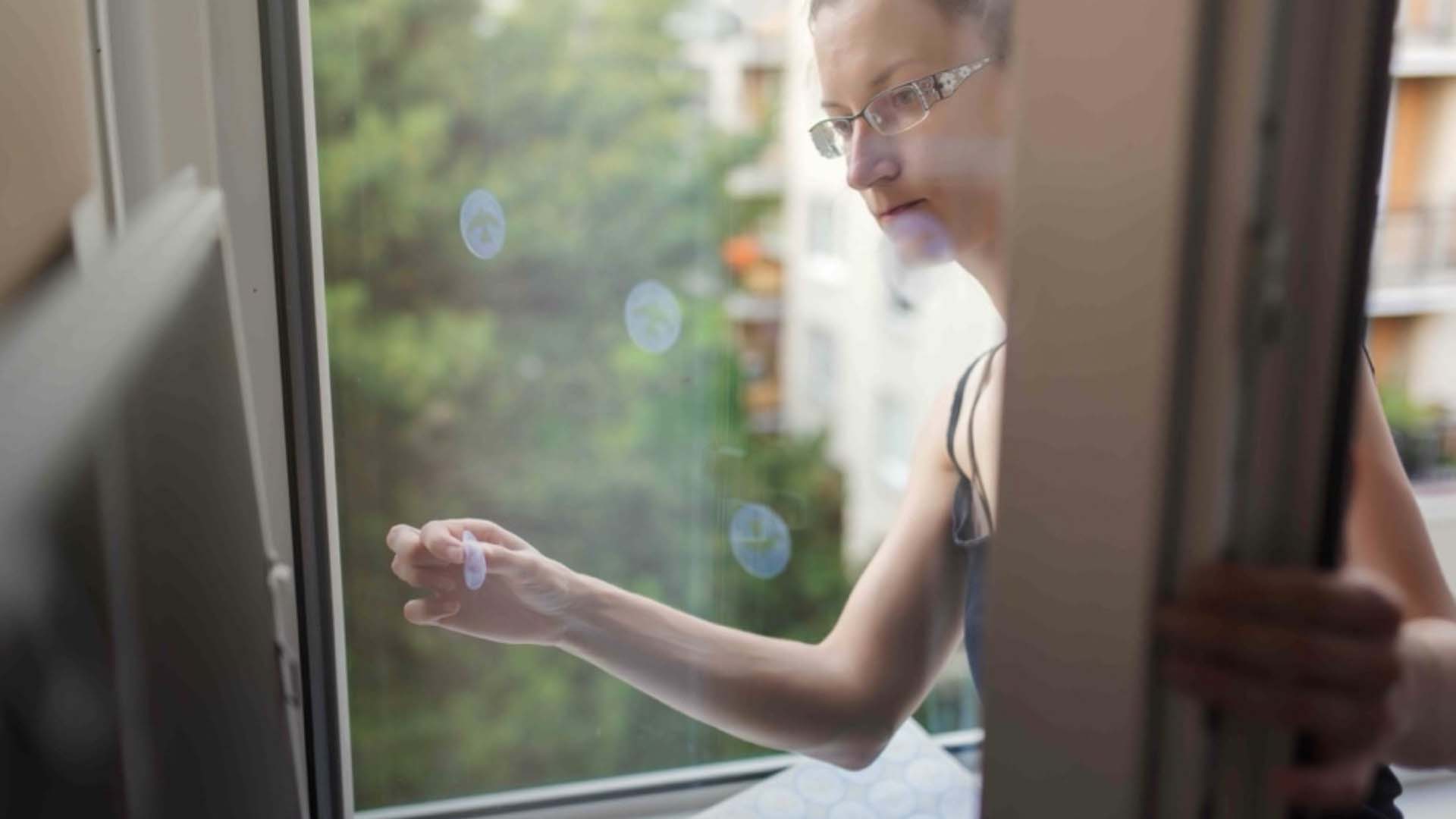 A close up of someone putting a sticker on a window