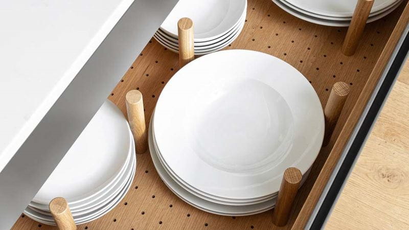 Pegs keep crockery from sliding across the drawer.