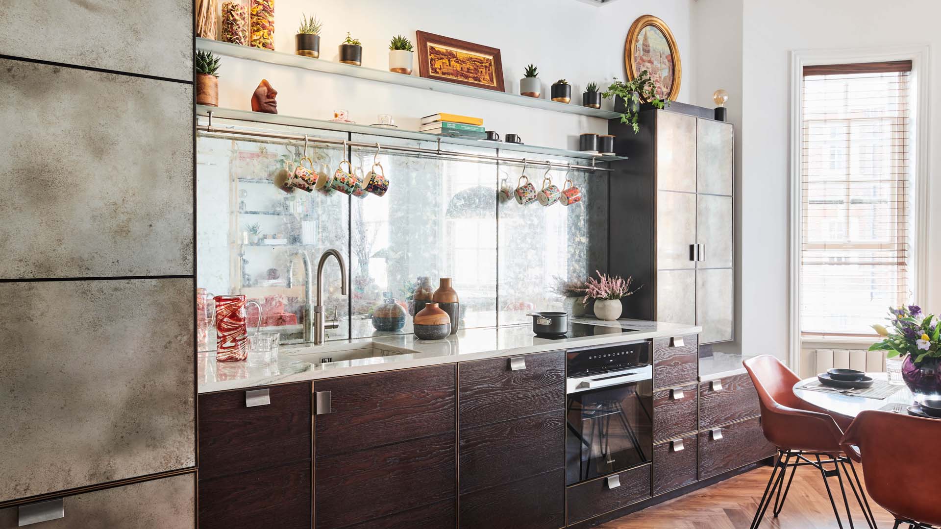 A kitchen with the sink in view and mugs on hooks