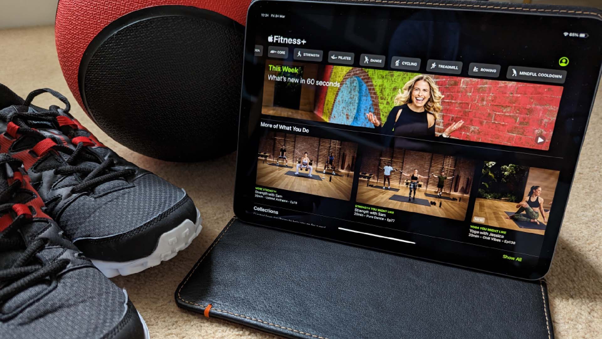 Apple Fitness+ on an iPad, with a pair of trainers and a medicine ball next to it.