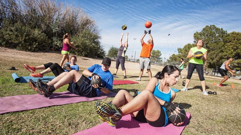 A group of people exercising on mats in a park