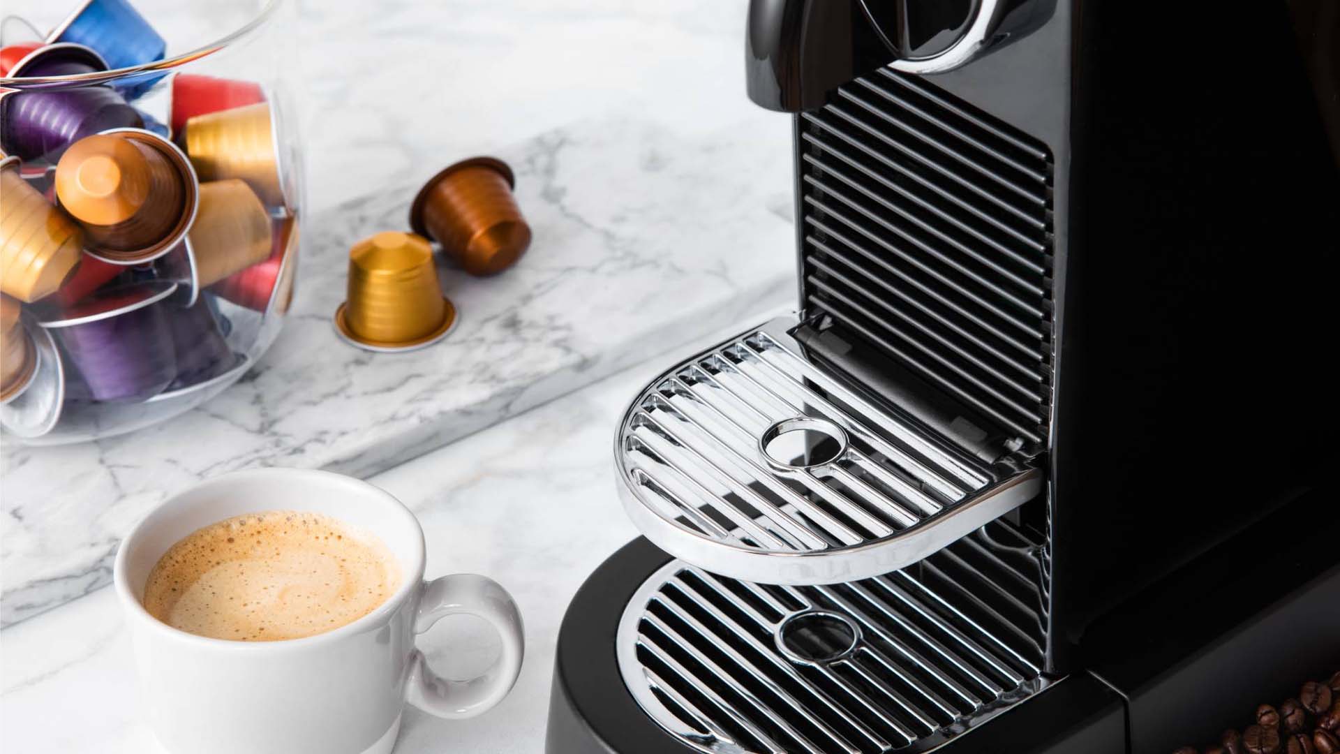 Close-up of a pod coffee machine with an espresso and container of coffee pods