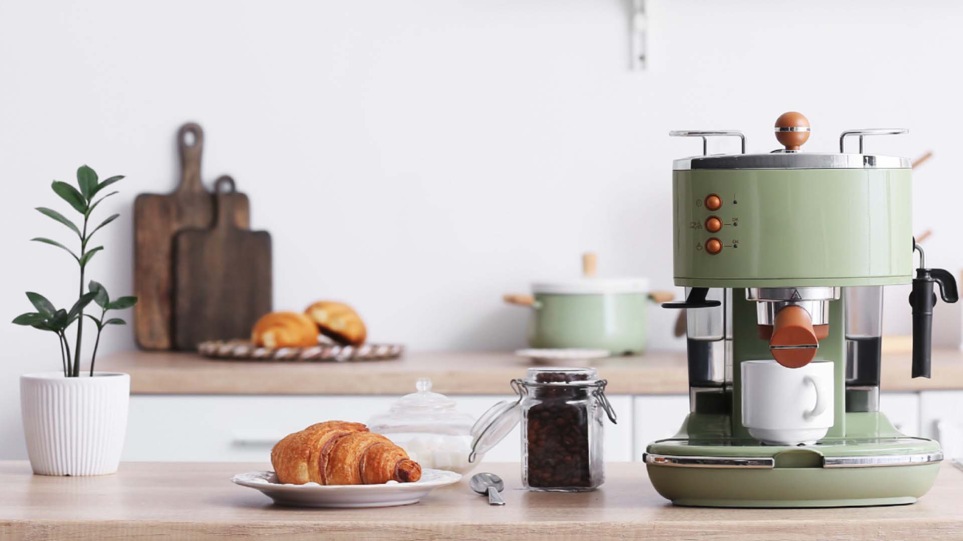 a green coffee machine next to a plated croissant