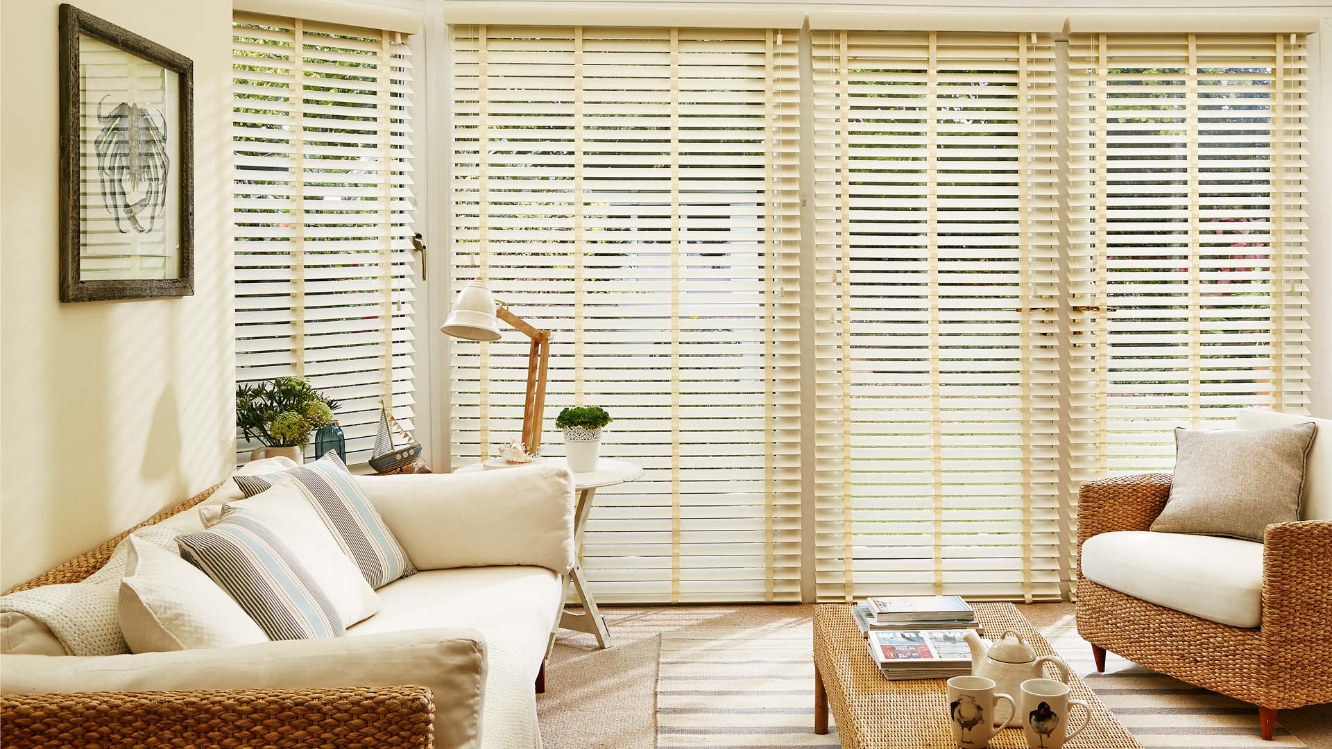 Interior view of a conservatory with closed white slatted blinds and furniture