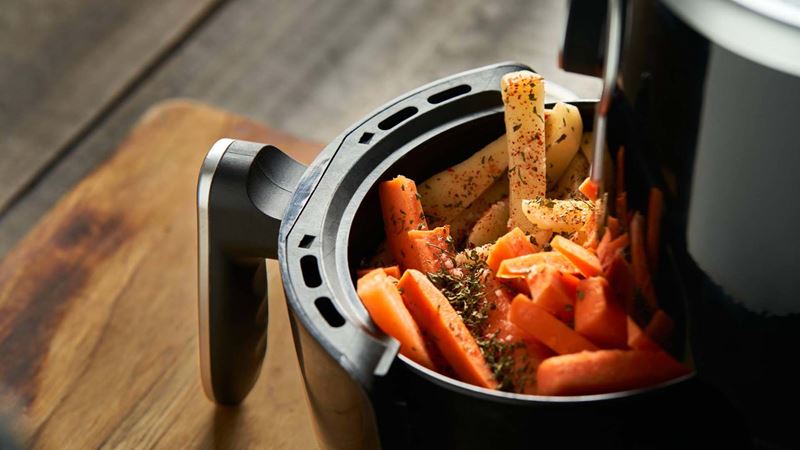 Vegetables, including carrots, cooking in an air fryer