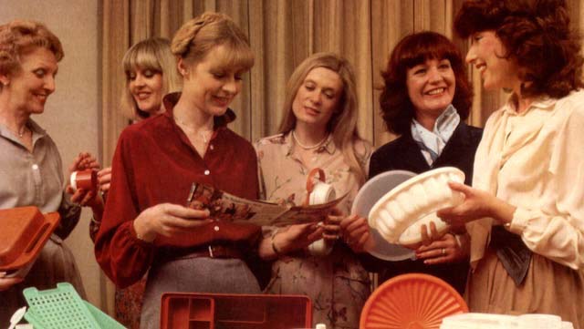 A vintage image of a group of women at a 'Tupperware party' holding various tubs and containers.