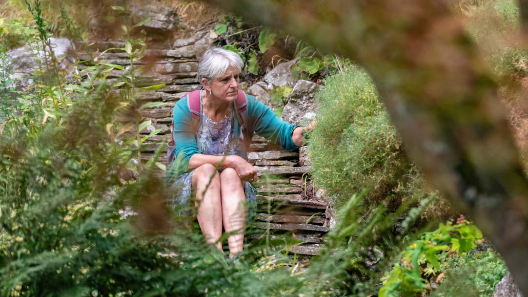 Woman sat on the middle of stone steps and a rockery