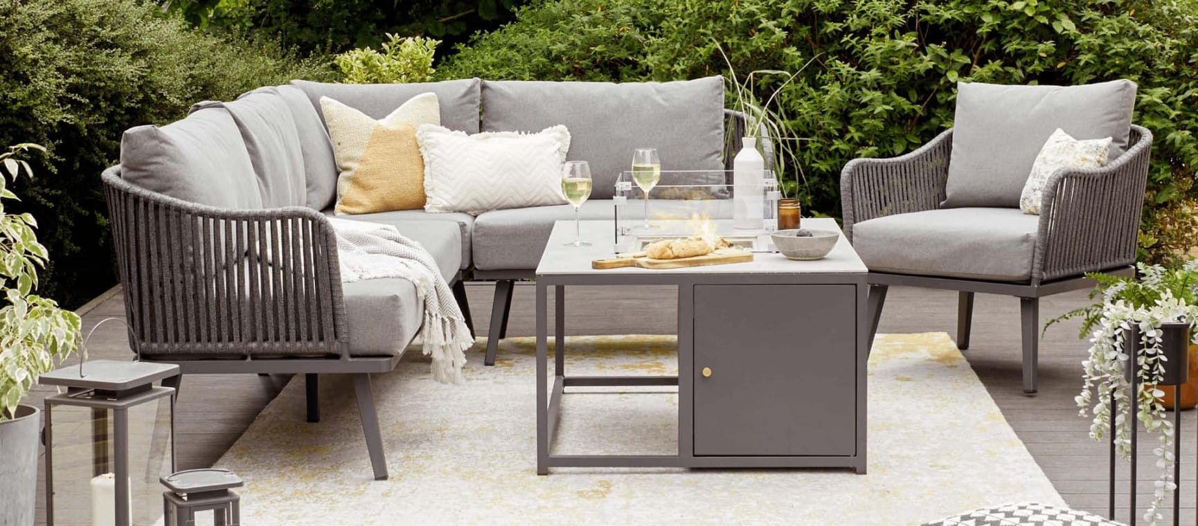 Light gray garden furniture set with extra cushions and drinks on the table