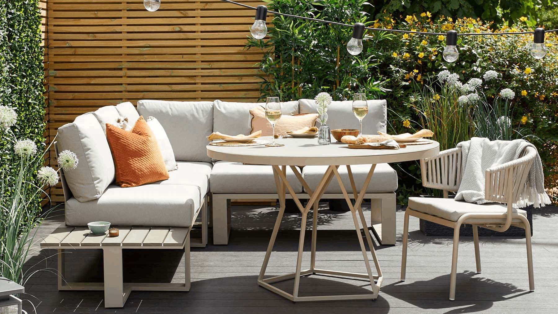 L-shaped light garden seating area with light cushions and round table