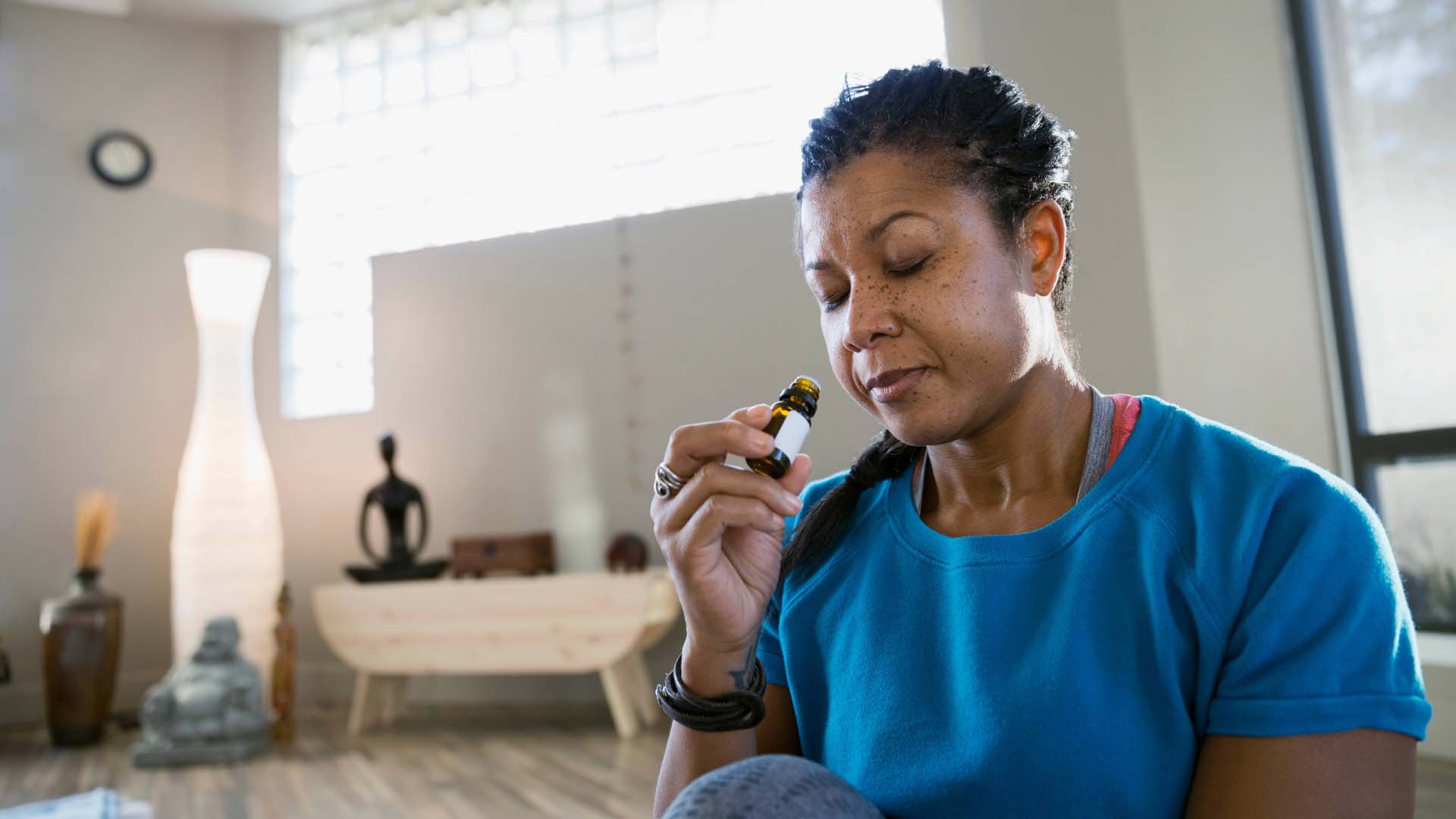 woman sitting in her living room smelling essential oils