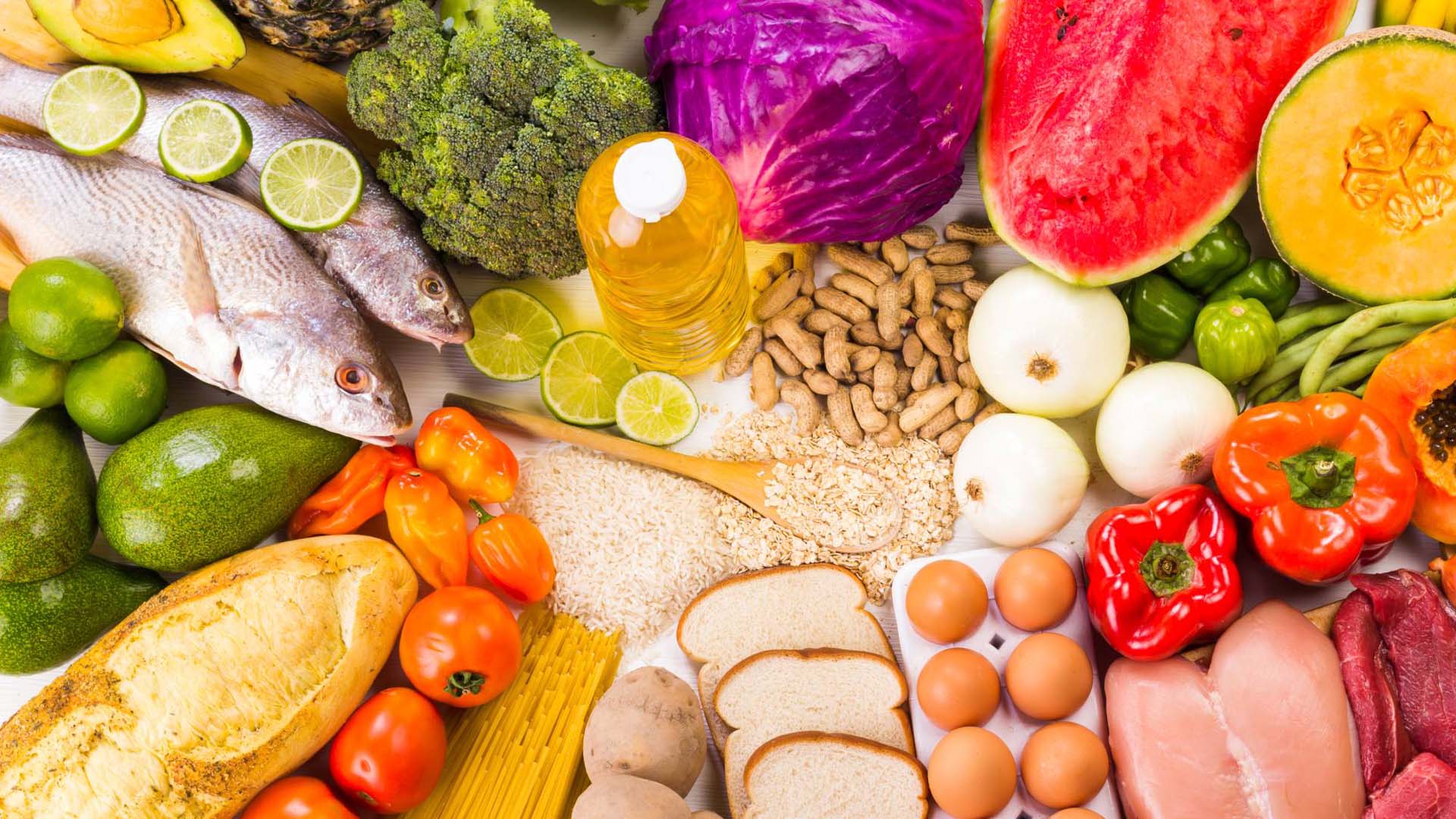 A colourful display of foods including fish, meats, fruits, vegetable, dairy products and nuts.