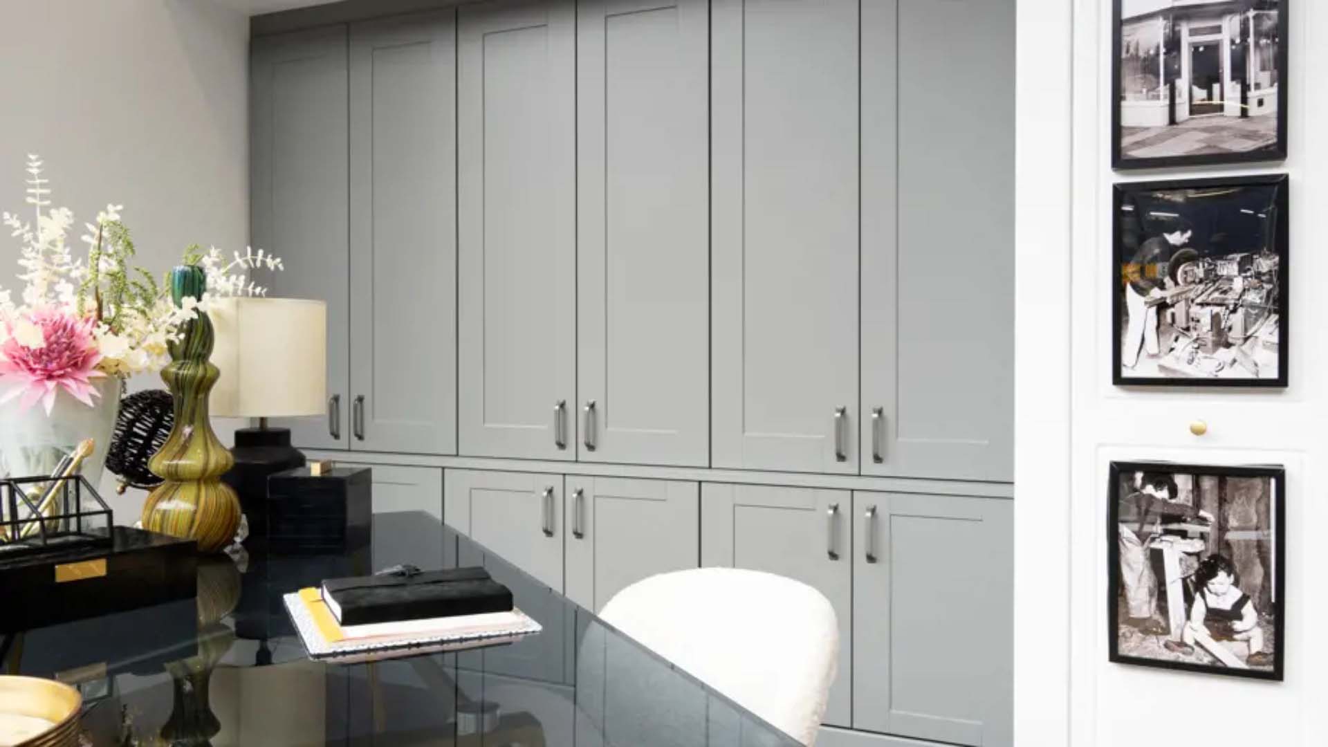 Grey floor to ceiling shaker style cupboards with black glass desk and white chair