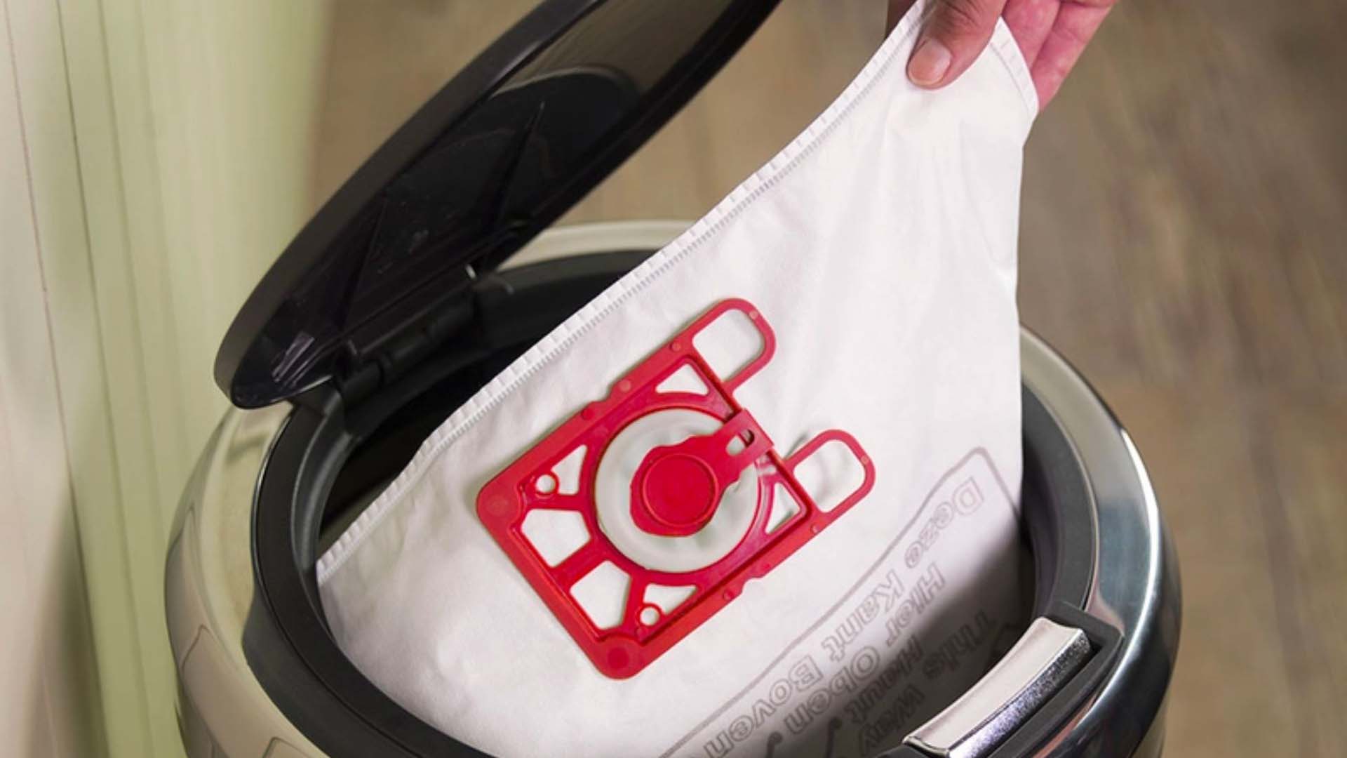 Close-up of someone putting a vacuum cleaner bag into a pedal bin