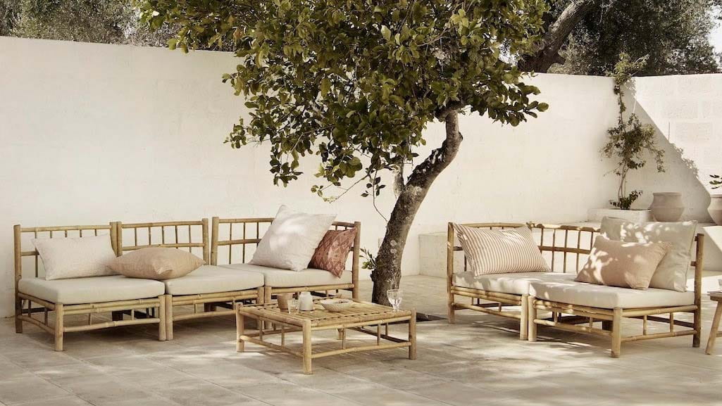 Modular bamboo garden seating in a bright white and cream patio with a single tree