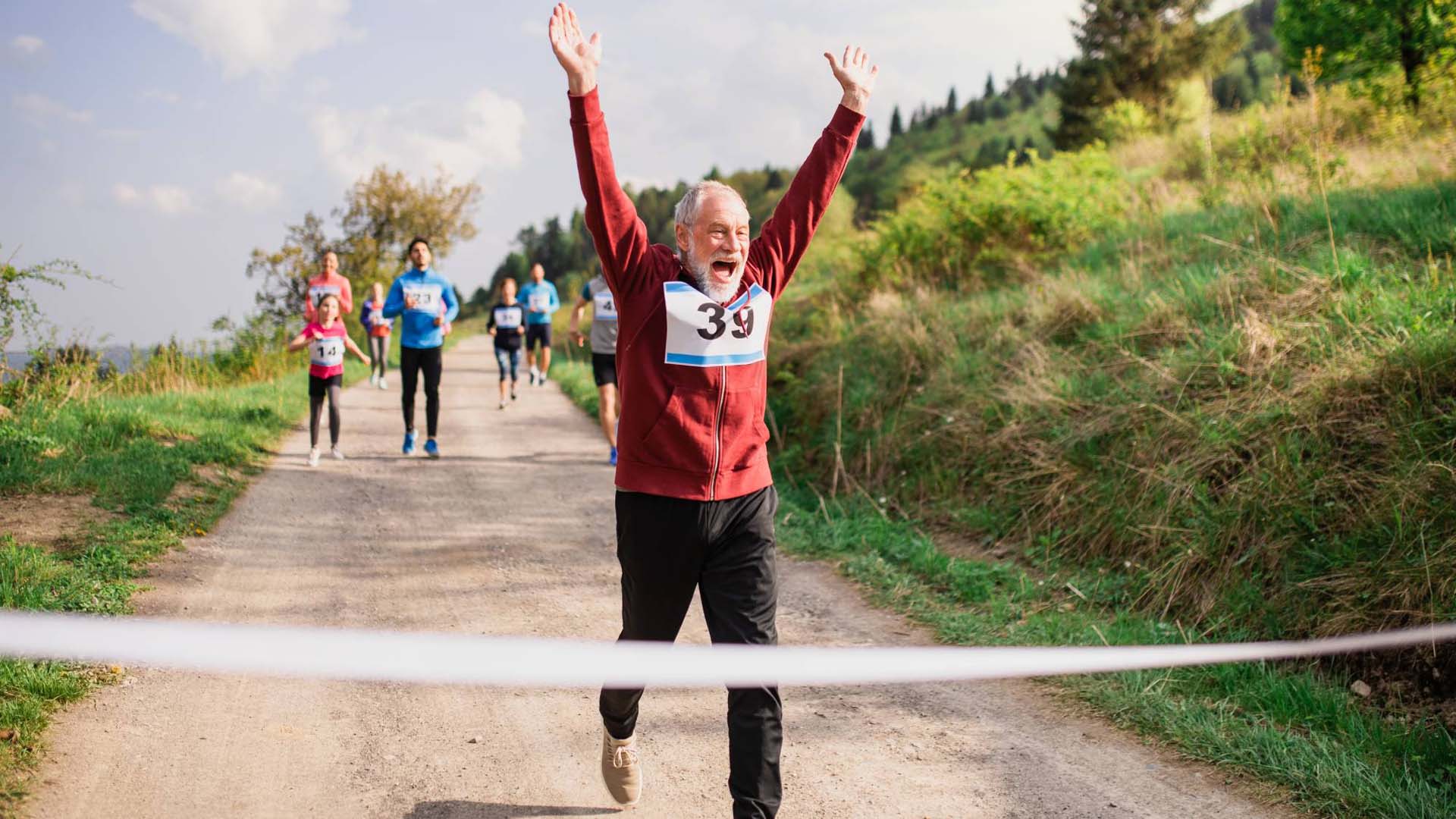 Senior man runner crossing finish line in a race competition in nature.