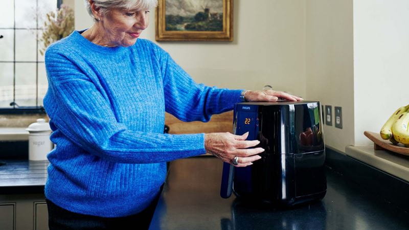 An air fryer being used by an older woman