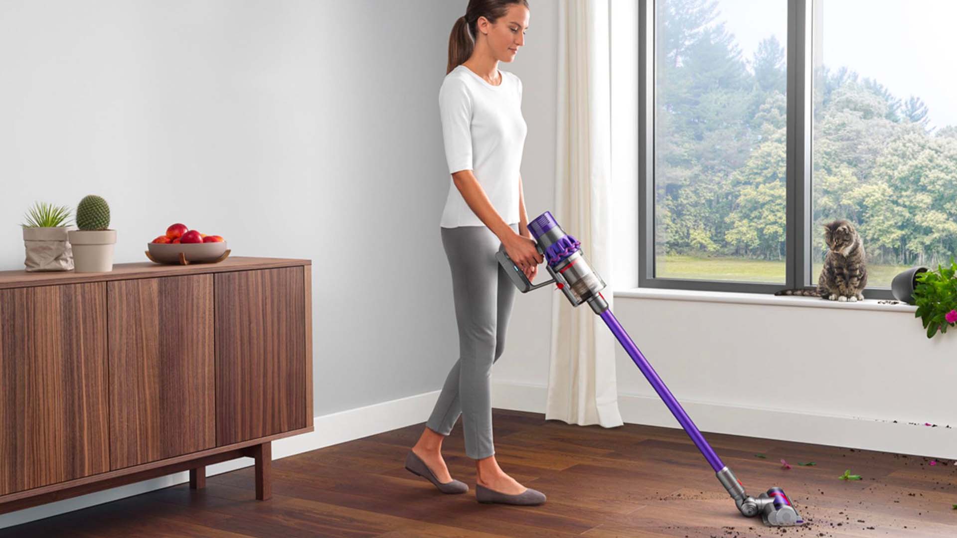  A woman uses a cordless Dyson vacuum on a wooden floor