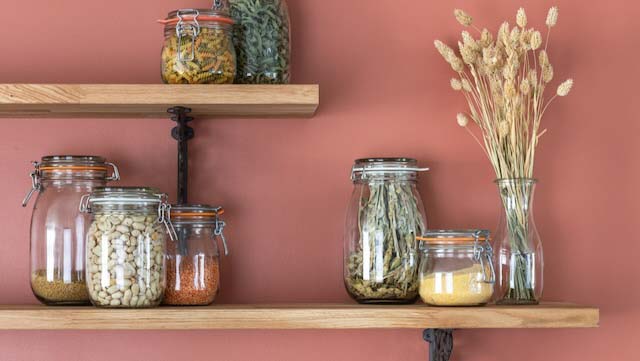 Kitchen shelves with glass jars for bulk products, terracotta wall