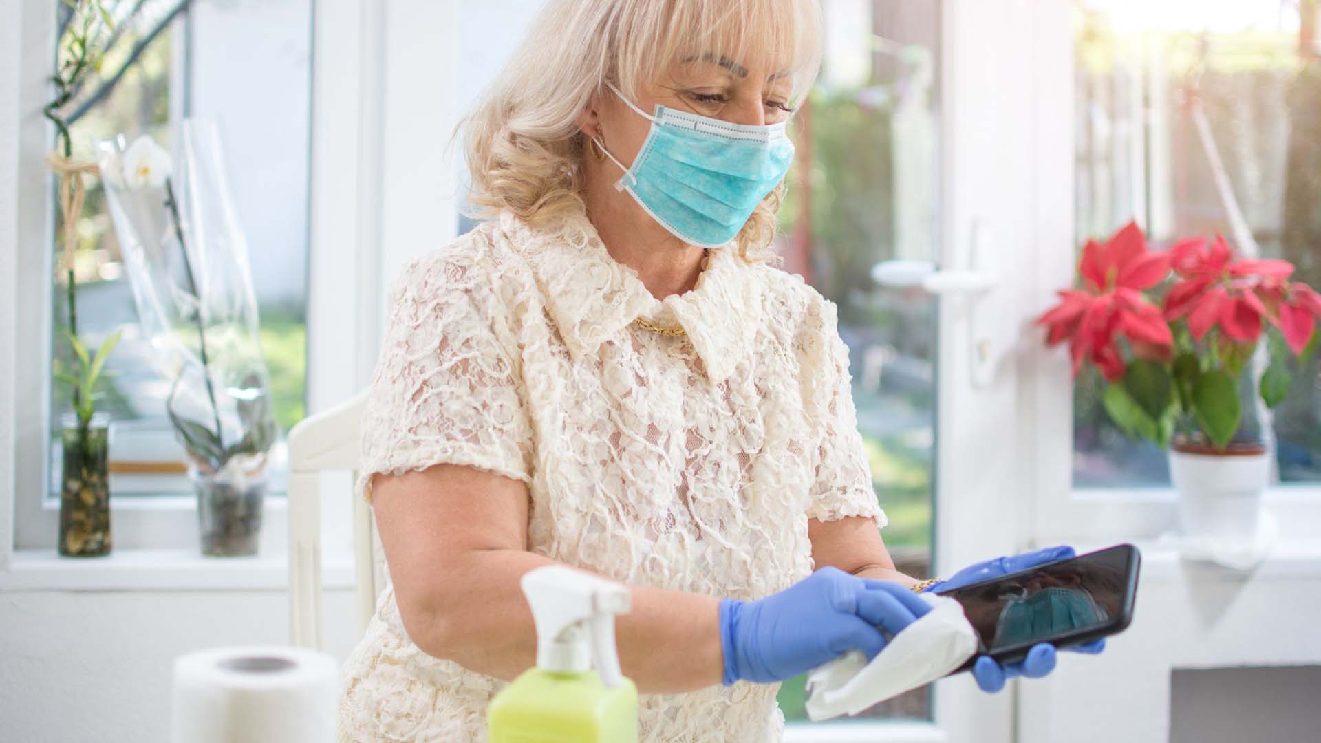 Masked woman cleaning dust in house