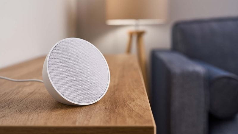 Close-up of an Amazon Echo Pop device on a side table in a living room