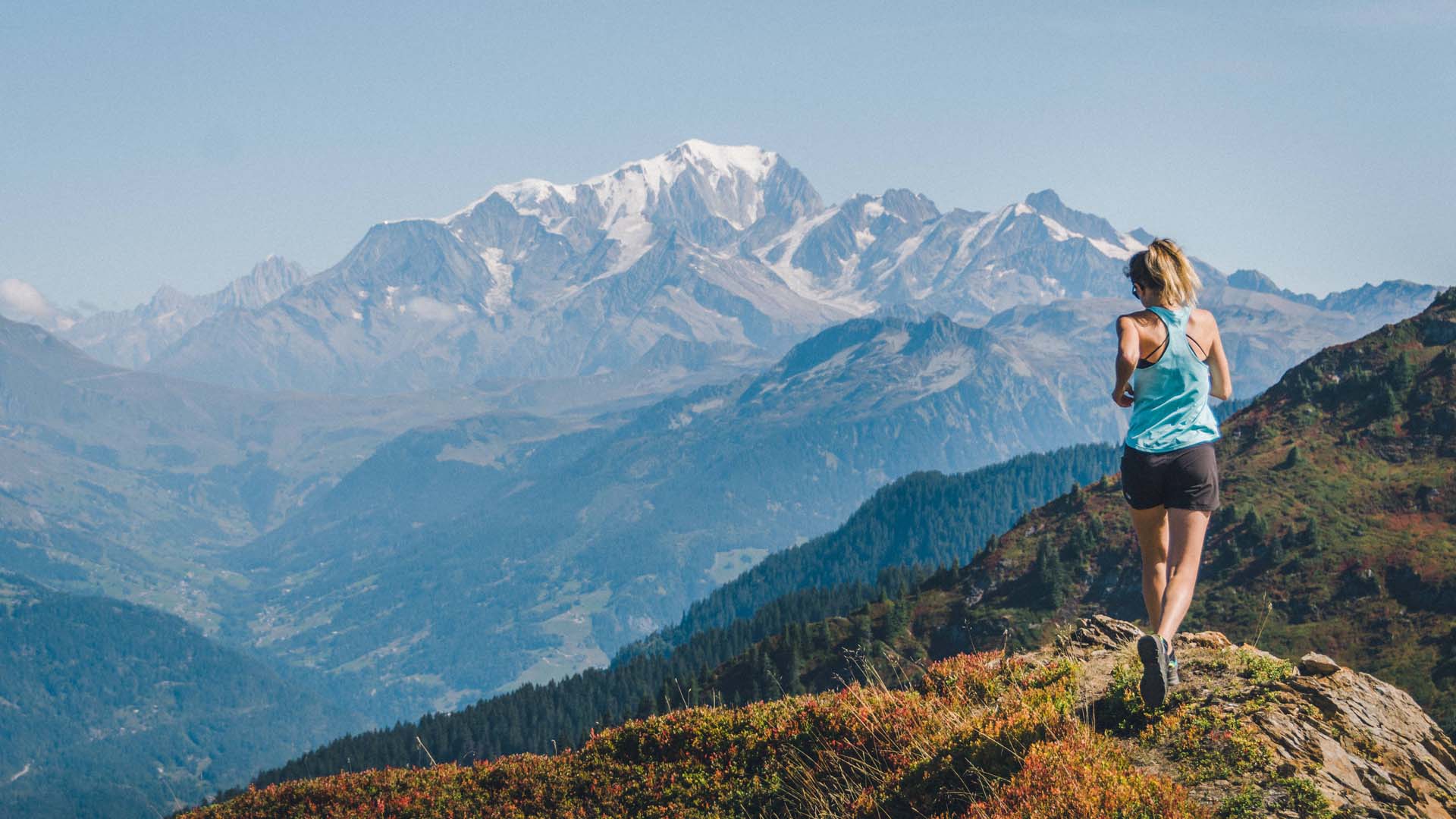 Trail runner enjoying the view as she runs along the top of a mountain