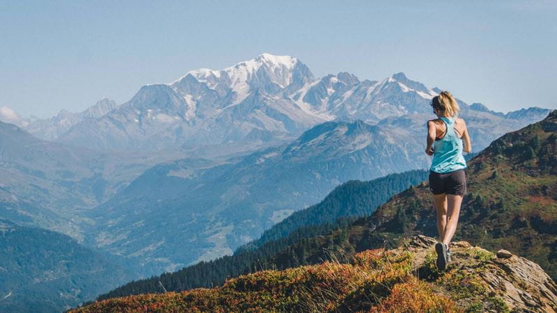 Trail runner enjoying the view as she runs along the top of a mountain