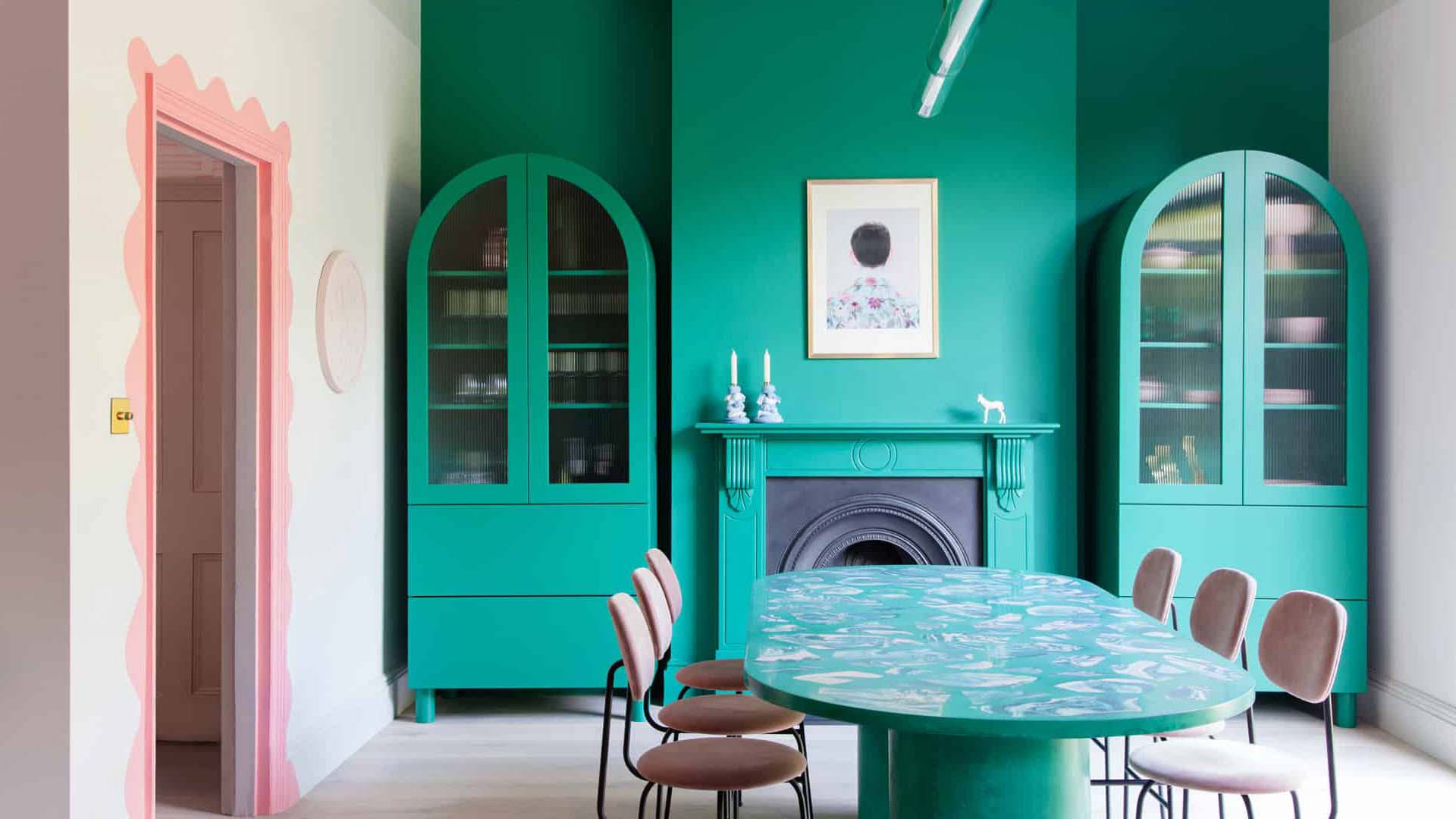 A dining room with one wall decorated in a vibrant green with matching glass-fronted cabinets