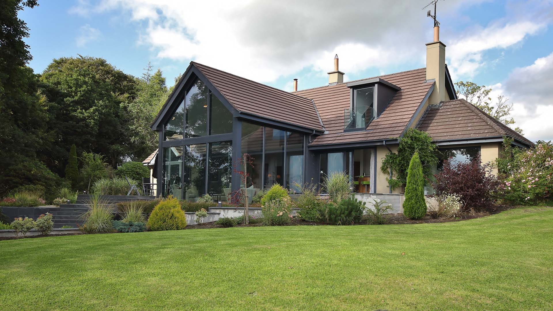 A large, tall conservatory with a tiled roof matching the adjoining house