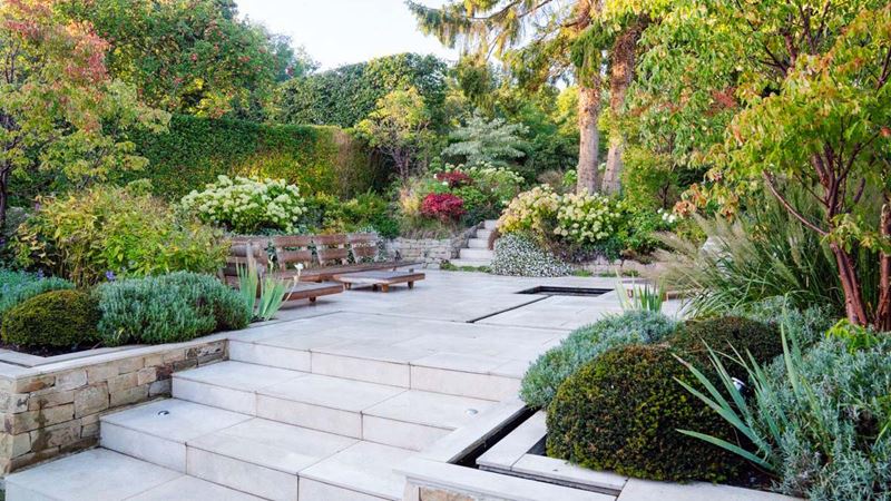 Grey stone steps up into a different tier of a garden