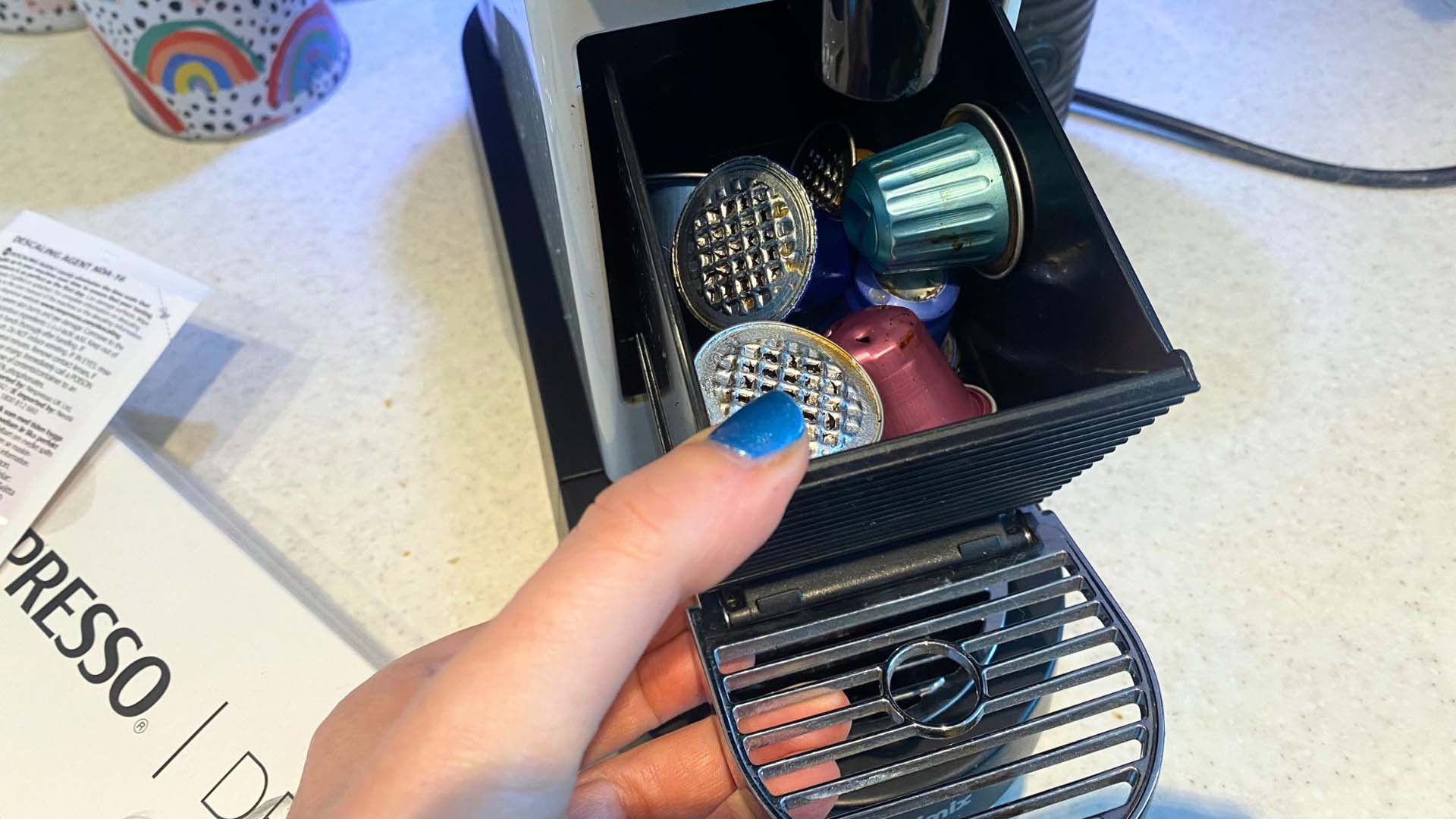 Close-up of a hand removing the used pods from a coffee pod machine