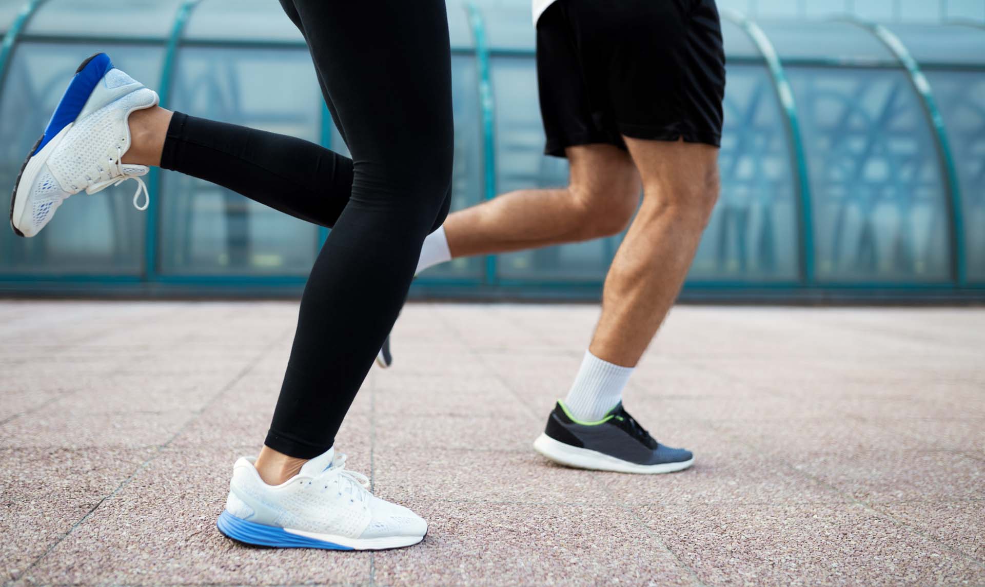 A male and female runner running along pavement showing just their legs. 