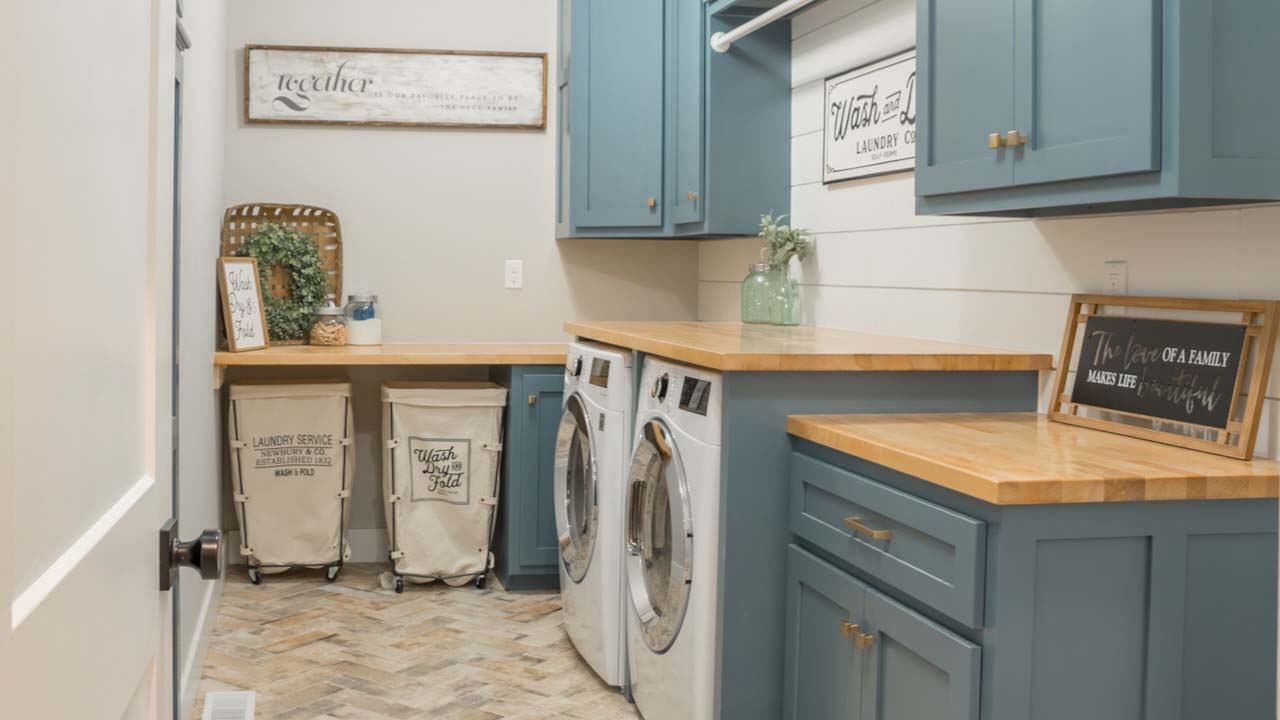 Farmhouse style laundry room, rolling carts, signs, blue cabinets.