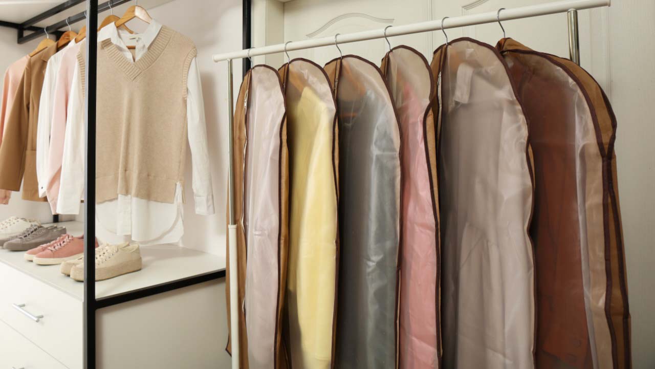 Garment bags with clothes on rack in dressing room