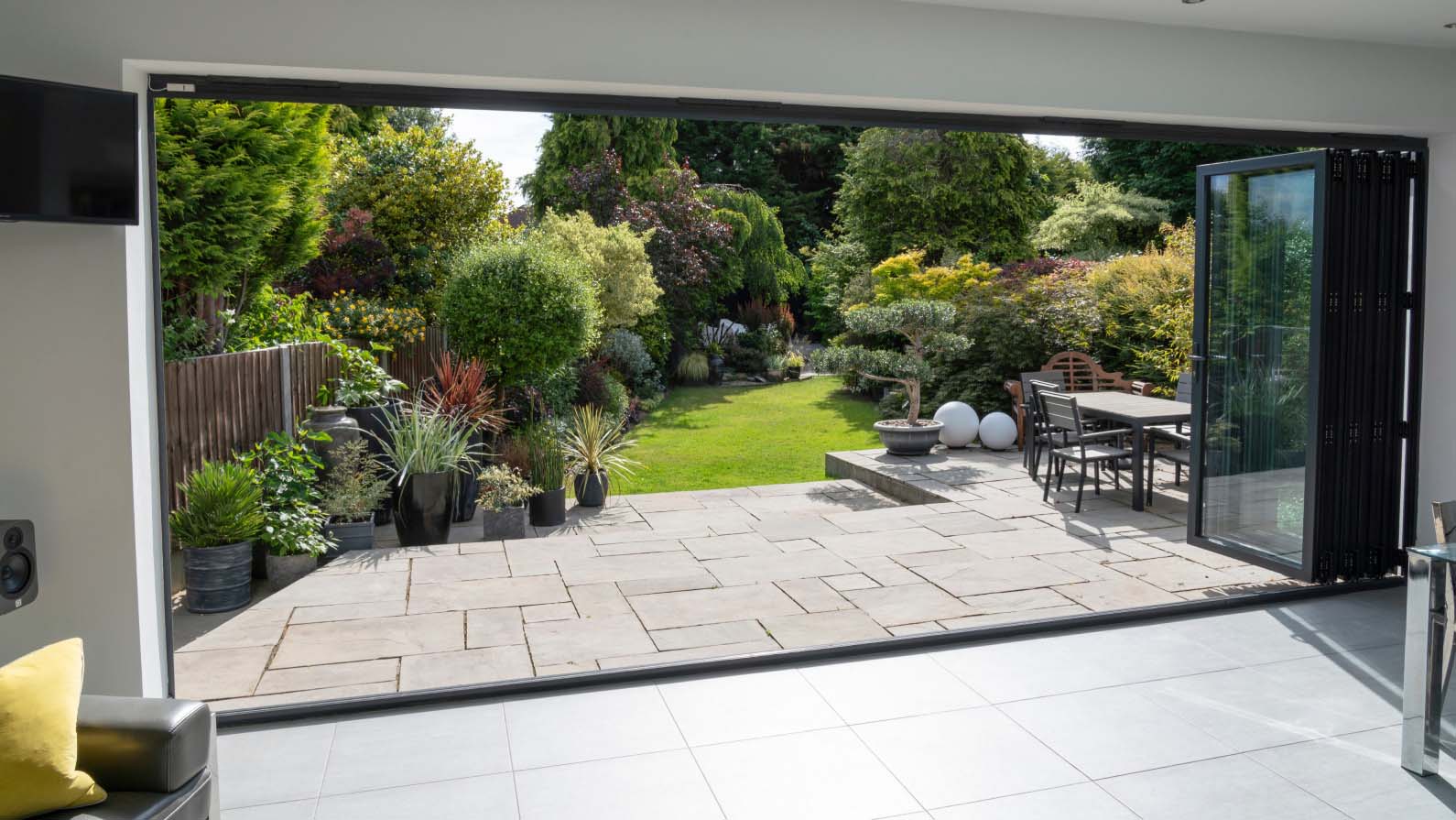 Beautiful garden and patio in summer seen from stylish designer room through bifold doors