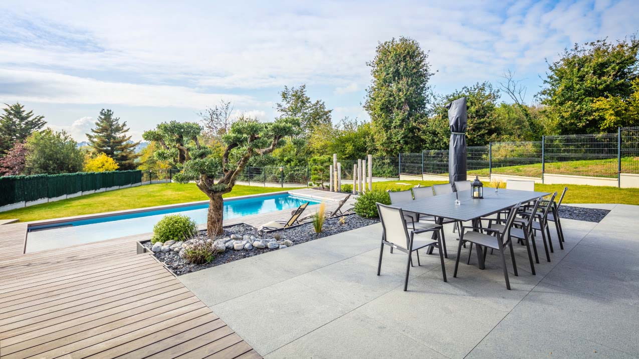 Terrace with a wood and marble deck area around the swimming pool in garden with a garden metal dinner table for 8 guests
