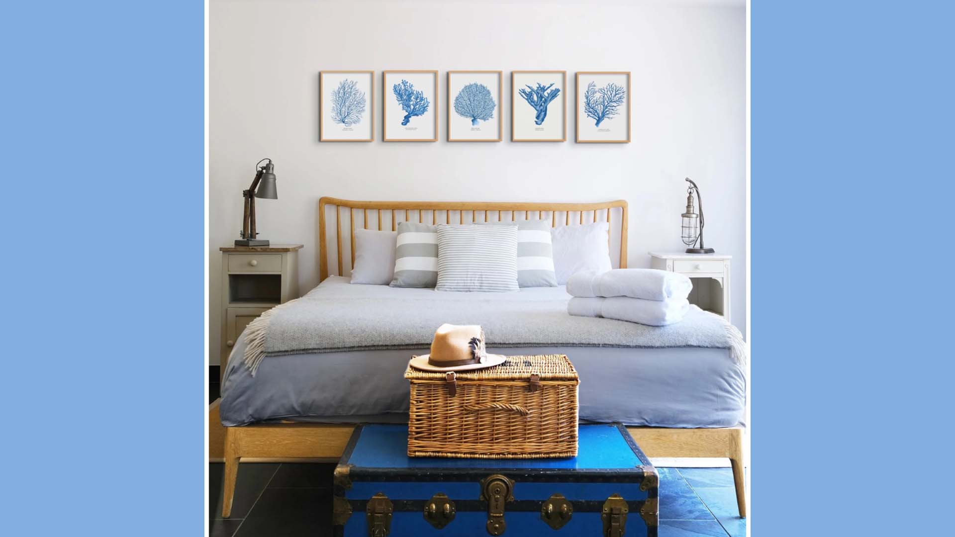 Doubled bed with bedding in shades of blue and white with a bar-style wooden headboard and prints of blue coral framed above.