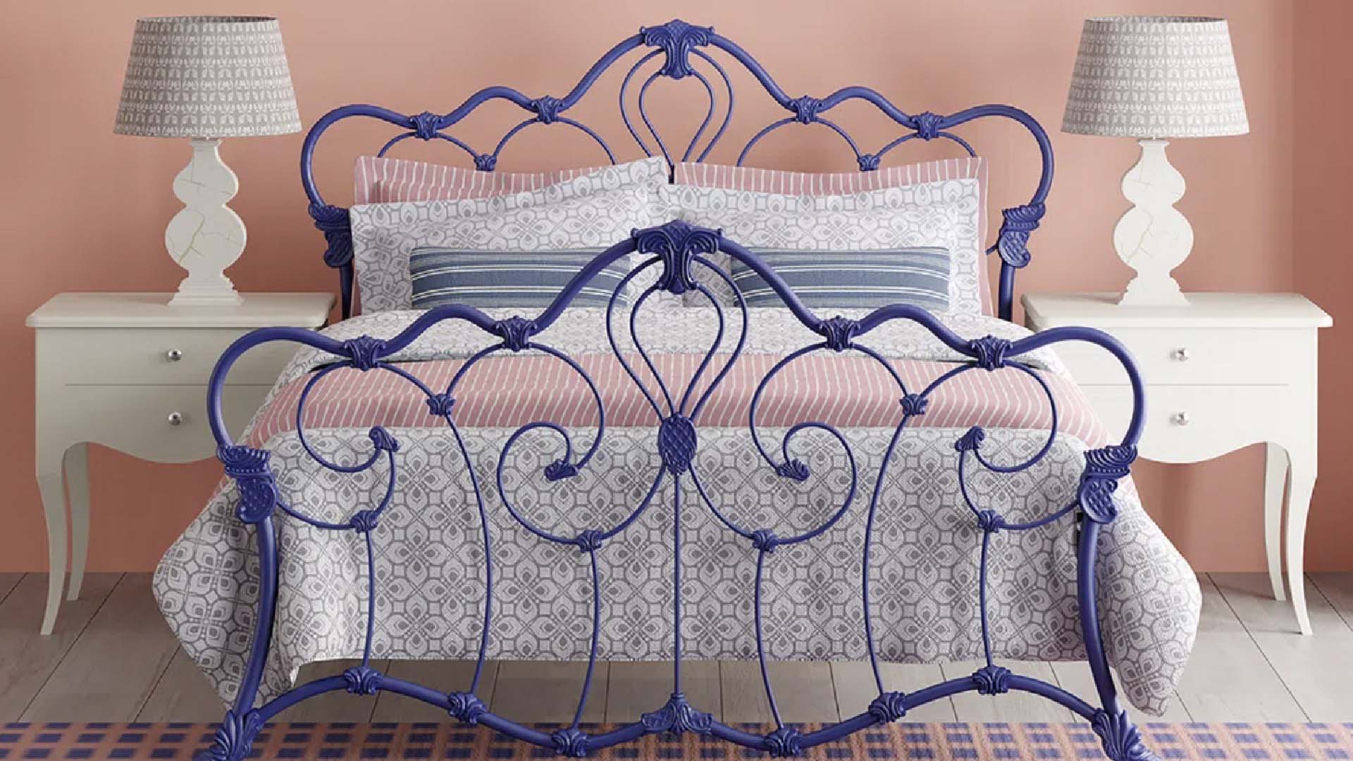 Blue ornate bed frame in a pink room